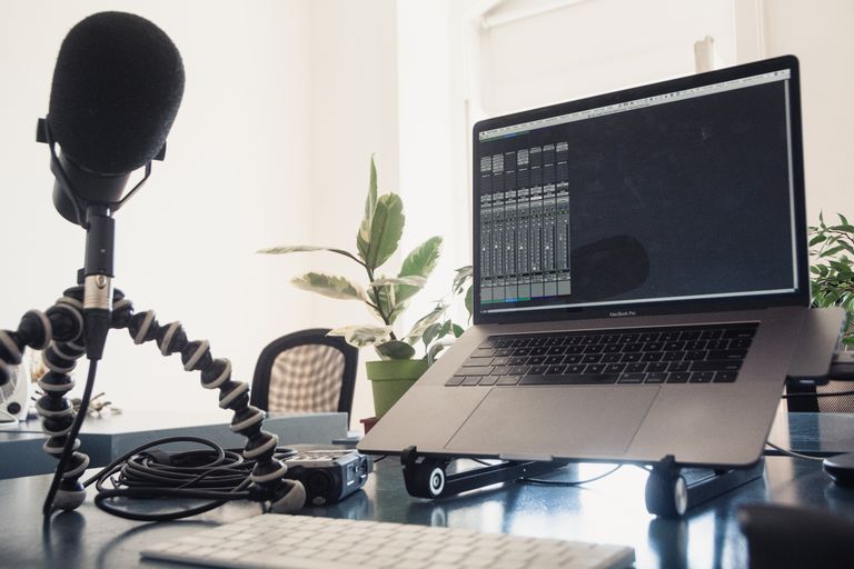 A detailed studio setup featuring a laptop and microphone on a desk for audio production.